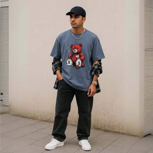 “Young man in urban streetwear styling an oversized blue graphic t-shirt with a red bear print, baggy black jeans, white sneakers, and a plaid flannel shirt, standing against a plain wall for a street-style fashion look.”